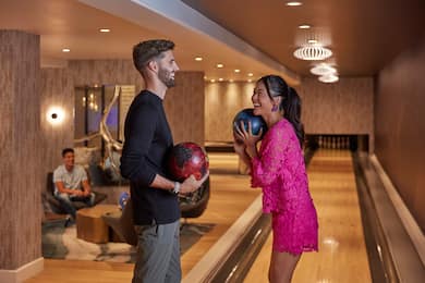 Group of people at bowling all, with man and woman holding bowling balls