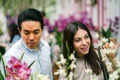 Asian couple stop to look at flowers in a botanical garden.