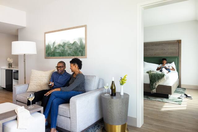 Brand Approved Placeholder Image of a family in a guest suite laying on the bed and watching TV