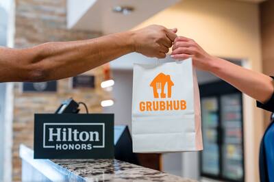 A person's hand passing a bag with the Grub Hub logo to another person