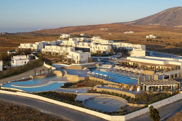 Overview of Hotel Exterior with Swimming Pools and Mountains in Background